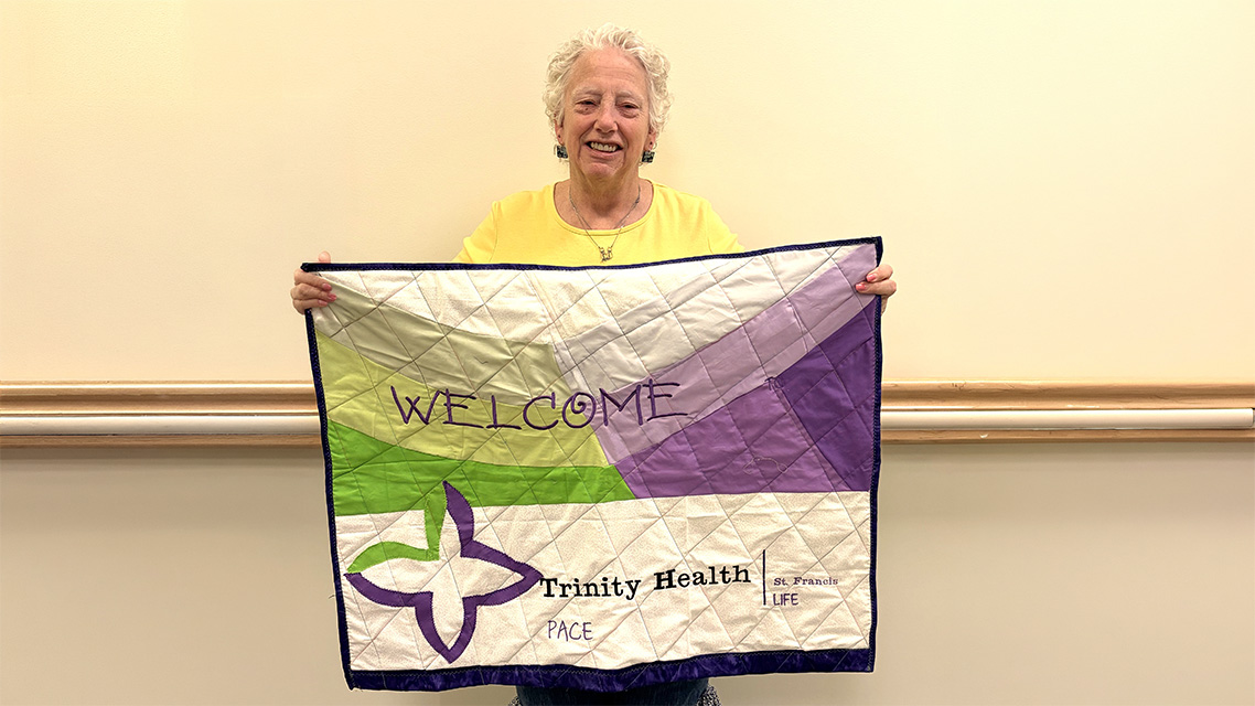 Participant displaying a handmade welcome banner featuring Trinity Health PACE branding.